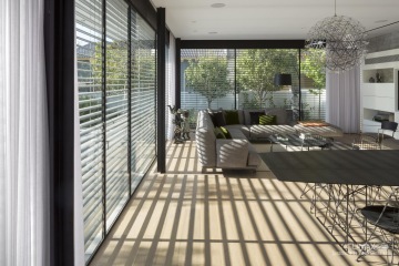 naklopené venkovní žaluzie focené z interiéru vrhají stín do místnosti